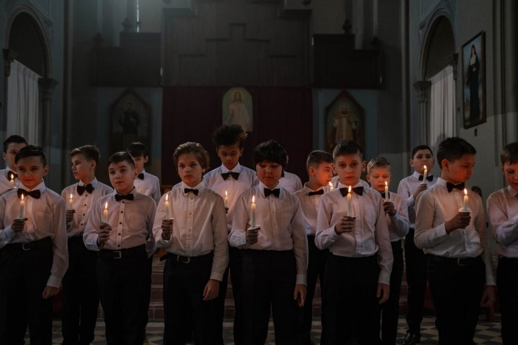 Boys in White Long Sleeves and Bowtie Holding a Lighted Candle